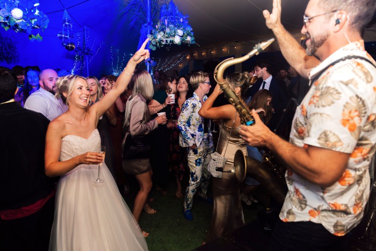 Paul Haywood performing live saxophone with Love DeluxX at a wedding reception in Cornwall. The bride and guests dance to an electrifying sax & DJ set, creating an unforgettable wedding party atmosphere.