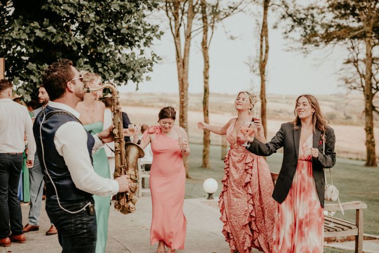 Paul Haywood (Paulonsax) performing a solo saxophone set during a wedding drinks reception at Tredudwell Manor, Lanteglos-by-Fowey, Cornwall. Guests enjoy classy, upbeat, and stylish entertainment in the elegant outdoor setting.
